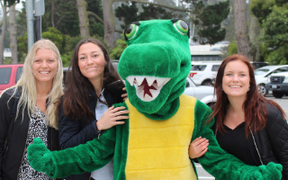 A green gator and exchange students at the orientation