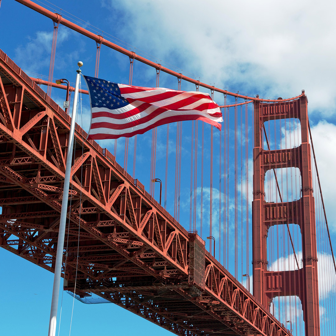 American flag on a poll in front of a bridge