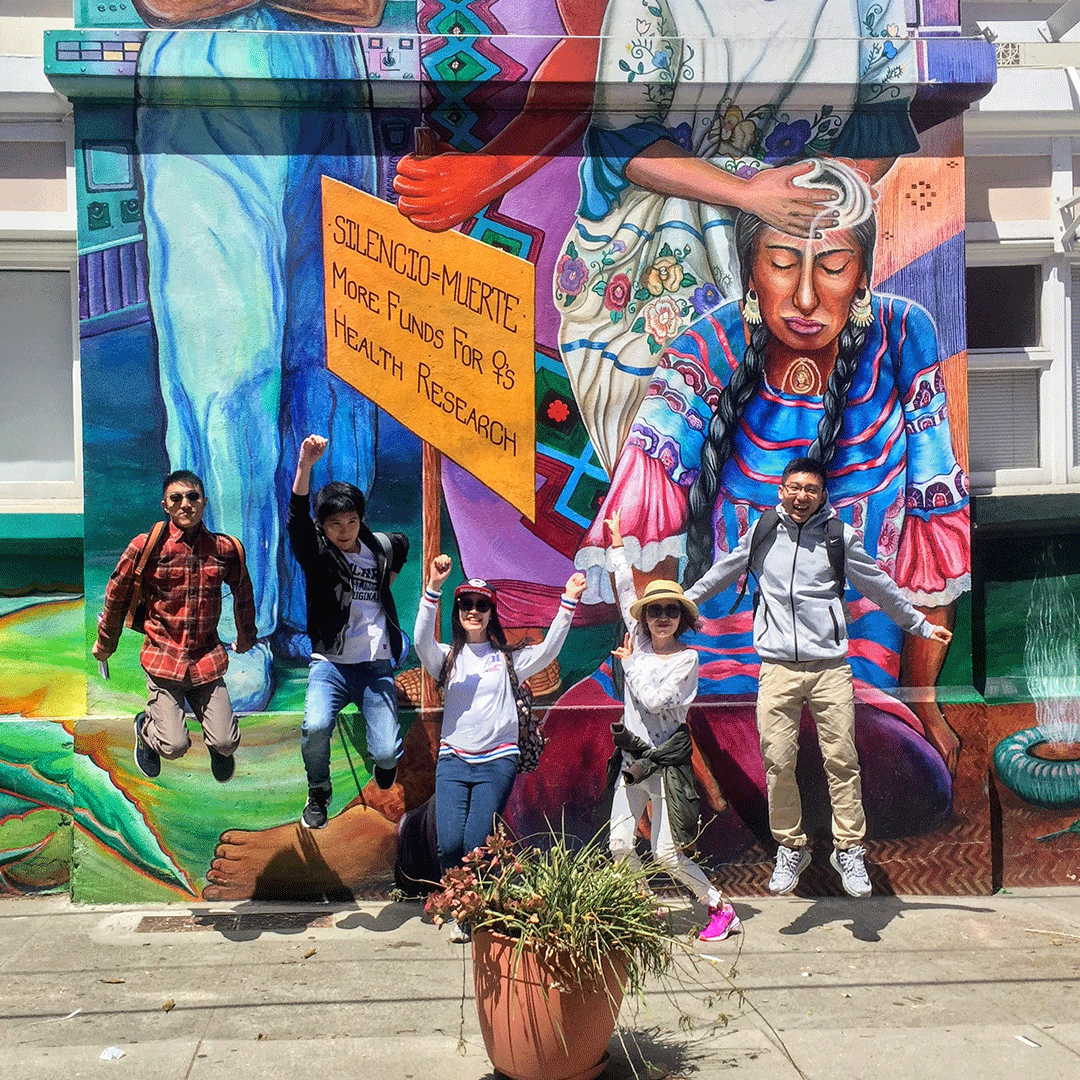 Students jumping in front of a mural