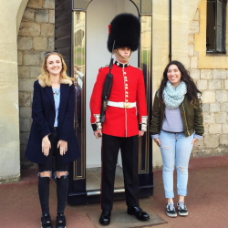 Two students with a guard in front of Buckingham Palace